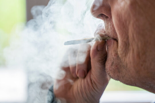Senior man at home smoking marihuana joint
