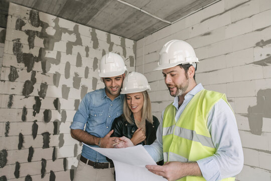 Architect talking about architectural plan with future owners on construction site