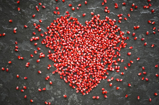 Heart shaped of pomegranate seeds on slate