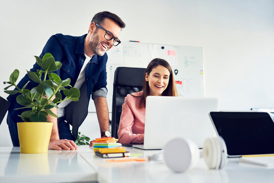 Two colleagues working together on laptop in office