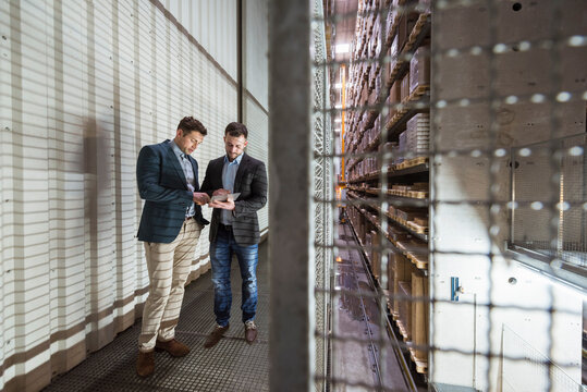 Two men in automatized high rack warehouse looking at tablet