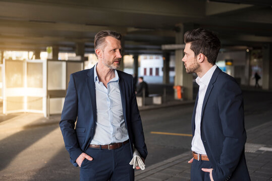 Two businessmen talking at bus terminal
