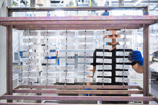Man working in factory shop floor hanging products on rack