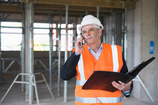 Man on the phone wearing safety vest in building under construction
