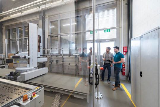 Two men looking at machine in modern factory