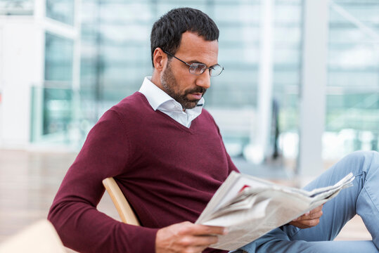 Businessman reading a newspaper in waiting hall