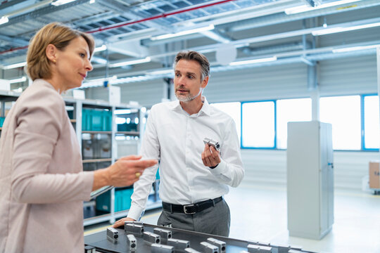 Businessman and businesswoman talking in a modern factory hall
