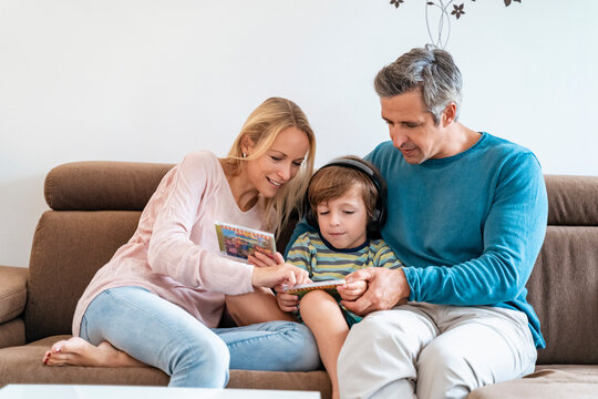 Family on couch at home with boy listening to music with headphones