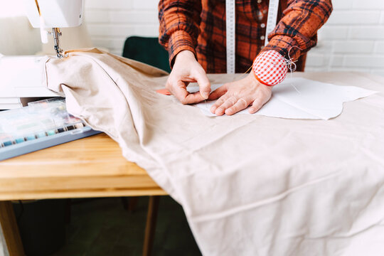 Close-up of woman pinning sewing pattern on table at home