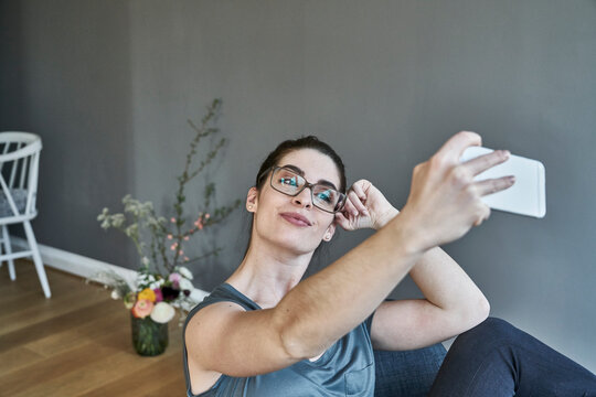 Smiling young woman taking a selfie at home