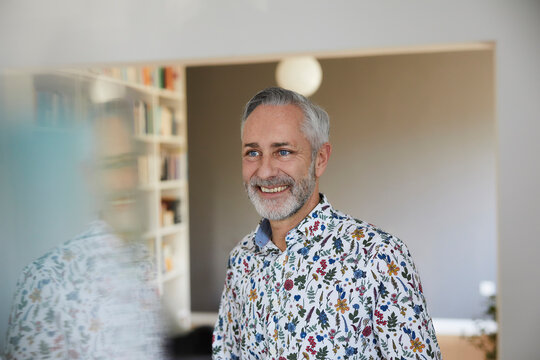 Portrait of smiling mature man wearing patterned shirt at home