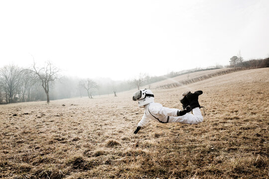 Boy wearing white space suit is posing outdoor on a meadow with virtual reality glasses
