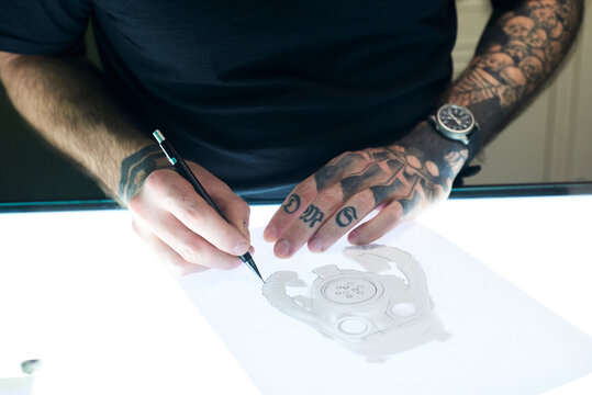 Tattoo artist designing motif on light table in studio