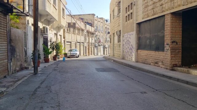 Quiet street in central Amman, Jordan, illuminated by soft morning sunlight, with empty roads, classic buildings, and a peaceful city atmosphere
