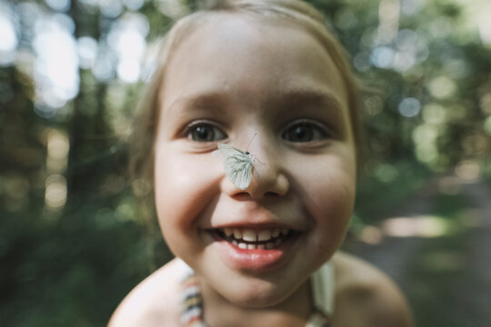 Portrait of smiling little girl with butterfly on her nose