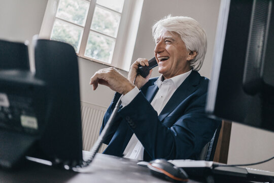 Laughing senior businessman on the phone in his office