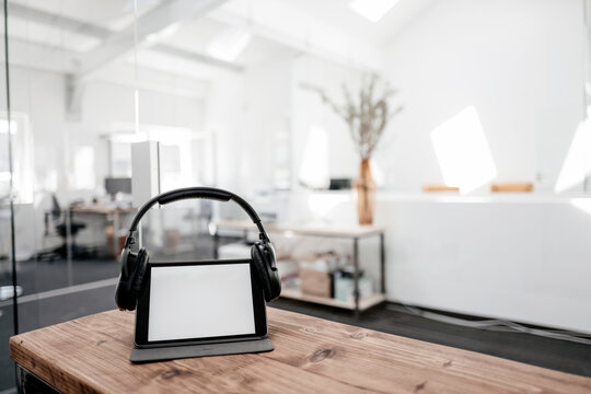 Tablet with headphones on wooden table in office