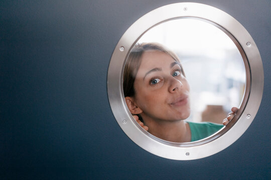 Portrait of woman peeking from behind porthole