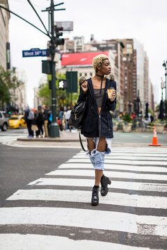 USA, New York City, fashionable young woman with coffee to go crossing the street