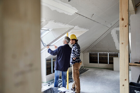 Architect and worker measuring window on a construction site