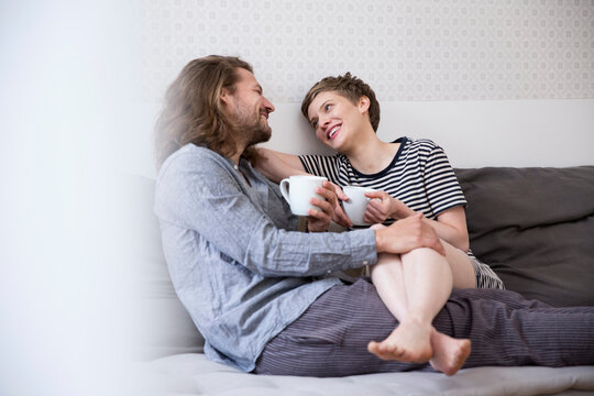 Happy young couple in pyjamas on bed couch at home