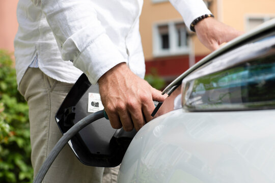 Man charging electric car at station