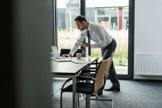 Businessman with atomic model using laptop in his office