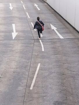 Rear view of businessman running on road with arrow signs