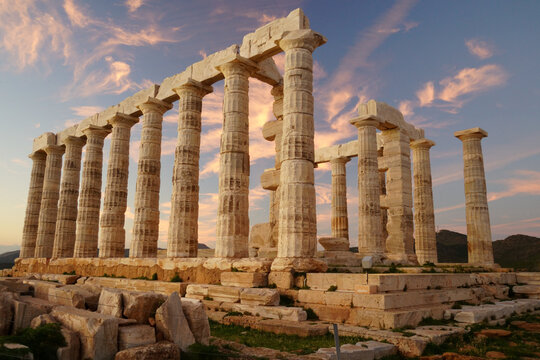 The ancient Greek Temple of Poseidon at Cape Sounion during a vibrant sunset with pink clouds