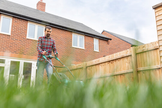 Man mowing lawn with lawn mower at backyard