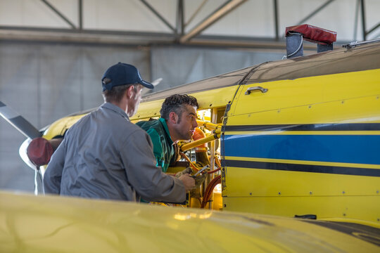 Mechanics in hangar repairing light aircraft
