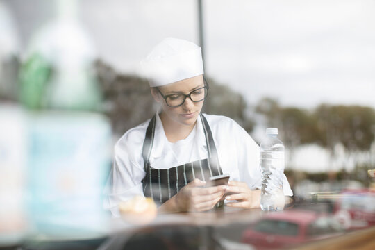 Woman in workwear checking cell phone at the window