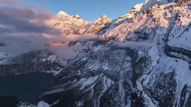 Aerial view of the stunning Oeschinensee lake nestled amidst snow-capped mountains and lush forests, a captivating scene of natural beauty, Kandersteg, Canton of Bern, Switzerland.