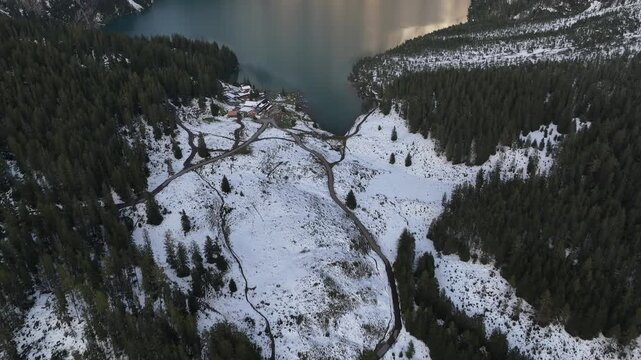 Aerial view of the Oeschinen Lake surrounded by snow-dusted mountains and lush forests, creating a striking contrast of colors, Kandersteg, Canton of Bern, Switzerland.