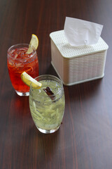Two glasses of colorful iced tropical drinks with shredded cucumber and basil seeds