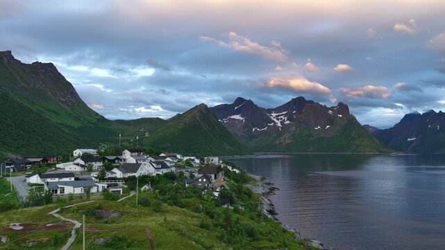 Aerial, forward drone flight, above Hus&oslash;y island and village Amazing wild nature during midnight sun in summer on Senja island in Norway. Beautiful landscape, wild nature. Fjord, mountains. Travel des