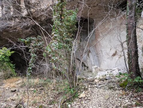 Interno di una grotta con rocce, muschio e luce naturale laterale; atmosfera selvaggia, texture geologiche, natura incontaminata, esplorazione, avventura.