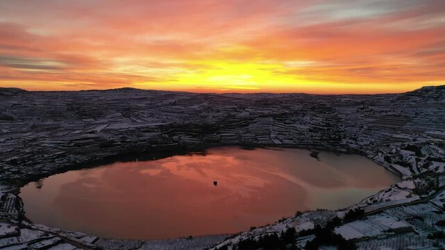 Aerial view of Lake Ram at a winter sunrise in the Golan Heights with the snowy Mount Hermon and Majdal Shams in the background