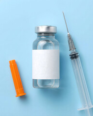 Blank Medical Vial and Unmarked Syringe on Blue Background Mockup
