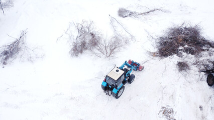 Blue tractor driving across snow-covered field in rural village © Andrey