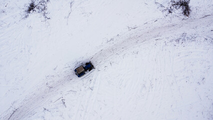Aerial top-down view of a blue tractor on a snow-cleared rural road