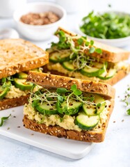 Delicious Hummus and Cucumber Sandwiches with Fresh Sprouts on White Surface