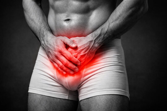 close-up of a man wearing white underwear, clutching his groin in pain. A red glow highlights discomfort, symbolizing a medical issue such as pelvic pain or prostate problems.	