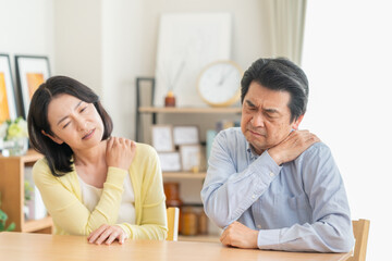 Fototapeta premium リビングで肩こりでマッサアージをするミドルの夫婦