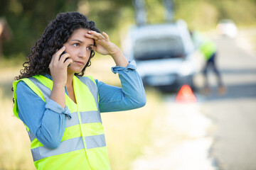 Fototapeta premium broken down woman wears reflective vest while phoning for assistance
