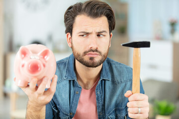 young man is breaking piggy money bank