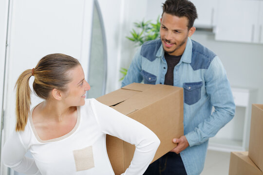 couple carrying a box indoors during a move