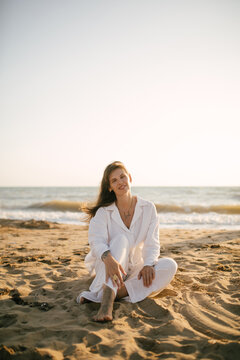 Beautiful 40 years old woman relaxing on the beach at sunset.