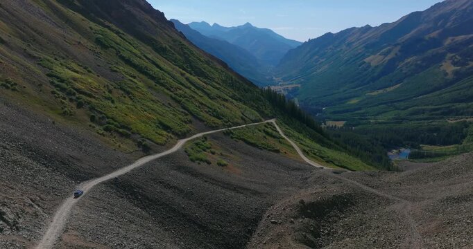 Ophir Pass reveals a steep cliffside road carved into unstable mountain slopes, rugged alpine environment of the San Juan Mountains Colorado, cars navigate