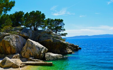 Fototapeta premium Peaceful lagoon with turquoise, clear sea, big rocks and green pine trees, Croatia